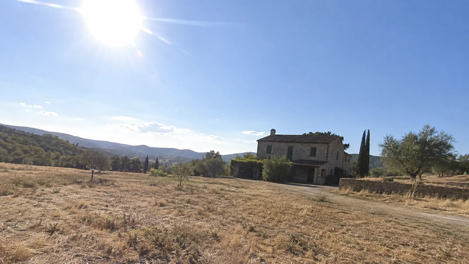 Fictional rural house shown from a distance in harsh light