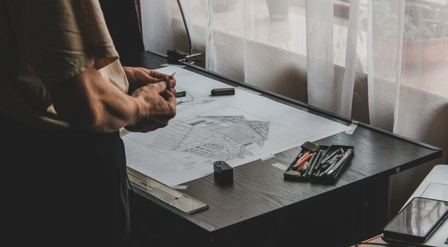 Arquitecto dibujando a mano alzada un croquis arquitectónico sobre la mesa de trabajo